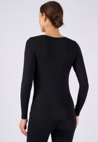 Top fitted a maniche lunghe nera con una texture liscia. Il design presenta un collo rotondo e maniche lunghe, adatto per essere indossato a strati.