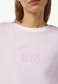 Jasnoróżowy sweatshirt z okrągłym dekoltem, z tonalnym haftem. Miękka tkanina z prążkowanym wykończeniem kołnierza.