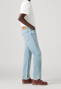 Ljust blå denimjeans med rak passform, med en läderpatch och två bakfickor. Matchat med en enkel vit t-shirt och röda båtlayer.