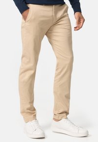 Khaki bomulds chinos med slim fit og sidelommer, der har en glat tekstur og et rent design. Kombineret med hvide sneakers.