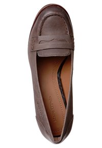 Mocassin en cuir marron avec un bout arrondi, des coutures décoratives et un petit motif découpé sur le dessus. Texture lisse et style à enfiler.
