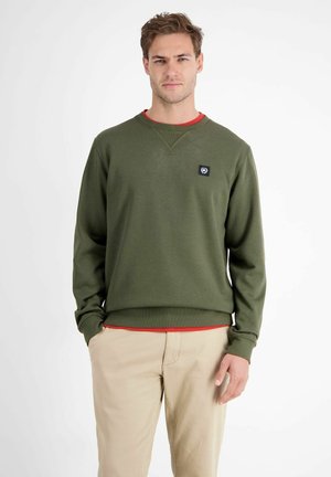 Green sweatshirt made of soft fabric, featuring a ribbed neckline and cuffs, with a small logo tag on the chest and a contrasting red layer underneath.