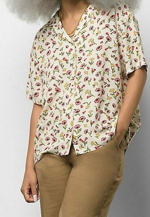 Bloemenprint shirt met korte mouwen en een beige achtergrond, met roze, gele en groene patronen. Losse pasvorm met een knoopsluiting aan de voorkant.