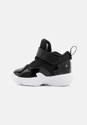 Zapatilla deportiva para niño pequeño en blanco y negro con cierre de velcro, parte superior de malla y piel charolada, lengüeta en el talón y logo Jumpman en el lateral.