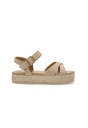 Sándal beige con diseño de tiras cruzadas, hebilla ajustable en el tobillo y suela de cuña de yute tejida para mayor altura. Textura suave en el material superior.