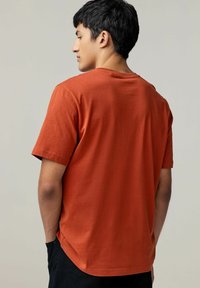 Rustfarvet bomulds T-shirt med korte ærmer, rund halsudskæring og lige kant, med en afslappet pasform og glat tekstur.