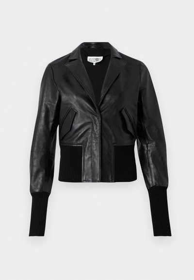 Juodas oda trumpas švarkas su pritaikytu apykakle, juostelėmis rankovėmis ir dviem priekinėmis kišenėmis. Lygus paviršius su blizgiu apdailos efektu.