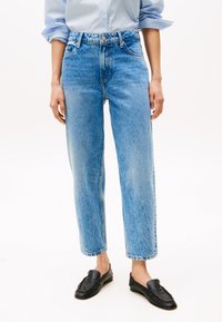 Jeans de mezclilla azul claro con cintura alta, corte recto y desvanecimiento visible. Presentan un diseño tradicional de cinco bolsillos y cierre de botón metálico.