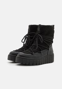 Botas negras hasta el tobillo con una superficie texturizada, forro de pelo sintético y suela de goma gruesa. Presenta cordones redondos y una lengüeta en la parte posterior.