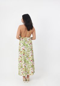 Blomster maxi kjole med grøn bund, prydet med pink og hvide blomster, åben rygdesign og justerbar snørredetalje ved udskæringen.