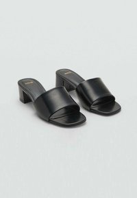 Black leather block-heeled mules with an open toe and wide strap across the foot, featuring a smooth texture and minimalistic design.