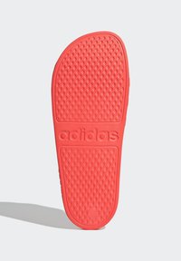 Rode rubberen sandaalzool met een textuurpatroon en het reliëf "adidas" logo. Rond ontwerp met een gladde rand.