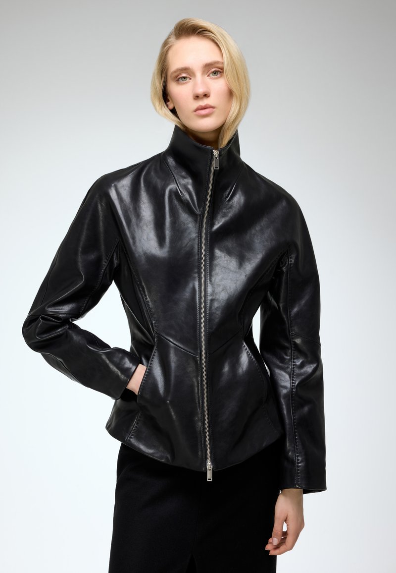 Black leather jacket with a high collar, fitted silhouette, long sleeves, and a central zip closure; smooth texture with subtle sheen.
