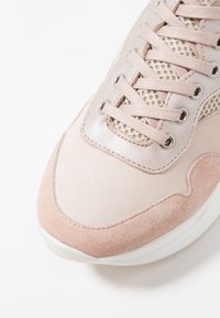 Světle růžové tenisky se zvířecími a síťovinovými detaily, metalickými očky a odpovídajícími růžovými tkaničkami na bílém pozadí.