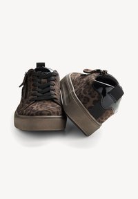 Baskets basses marron à imprimé léopard avec lacets noirs, fermetures éclair latérales, semelles épaisses couleur tan et accents au talon en cuir verni noir, présentées sur fond blanc.