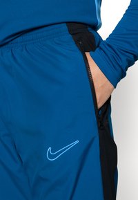 Nike Performance NIKE ACADEMY23 TRACK PANTS - Donji dijelovi trenirke - green abyss/black/baltic blue
