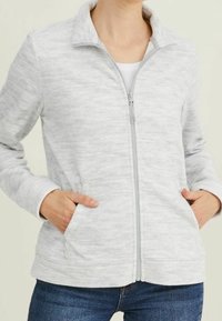 Šedá zipová bunda vyrobená z texturem s lehkým materiálem, se bočními kapsami a stojacím límcem. Ideální pro volnočasové nošení.