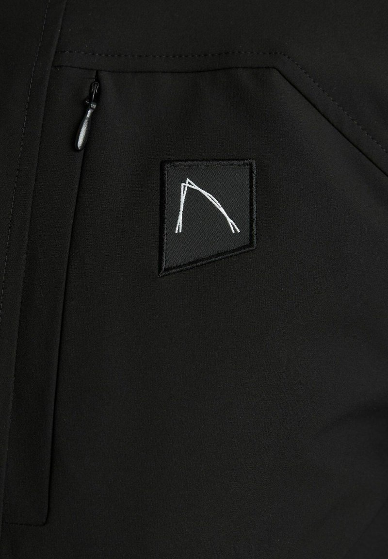 Czarna kurtka z zamkniętą kieszenią i kwadratową naszywką z białym wzorem, wykonana z gładkiego materiału o matowym wykończeniu.