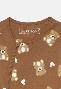 Macacão castanho com fecho éclair, apresentando um padrão de ursos e detalhes em forma de coração brancos. Fabricado em tecido suave com uma textura canelada. Tamanho 3-6 meses.