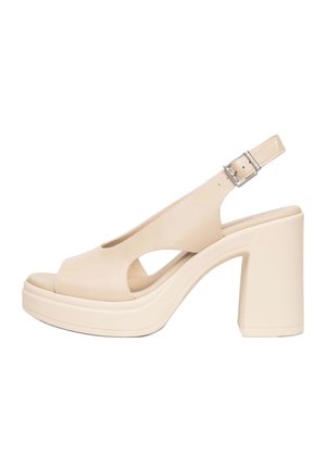 Sandale beige à plateforme ouverte avec talon haut épais et bride cheville avec fermeture à boucle argentée.