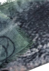 Sciarpa in tonalità di verde e grigio spenti, con un motivo testurizzato, bordi frangiati e un tessuto morbido e leggero.