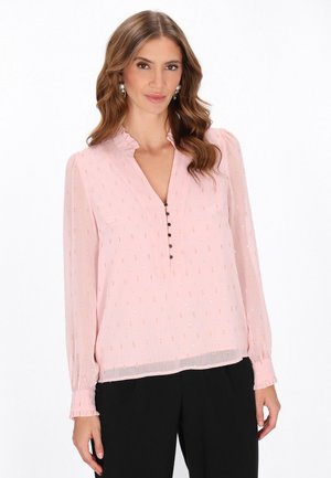 Lichtroze blouse van sheer stof, met een volantsboord, knopen en metalen versieringen. Lange mouwen met geplooide manchetten.
