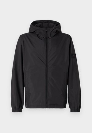 Czarna, lekką kurtka z kapturem, zamek błyskawiczny, elastyczne mankiety i boczne kieszenie. Posiada naszywkę z logo na lewym rękawie.