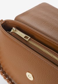 Borsa a tracolla in pelle marrone con superficie testurizzata, dotata di una zip dorata, di una tracolla a catena intrecciata e di un particolare fermo metallico.