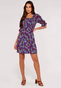 Blumenmuster-Kleid mit quadratischem Ausschnitt, Puffärmeln und tailliertem Schnitt. Der Stoff ist leicht und hat ein mehrfarbiges Muster auf einem dunklen Hintergrund.
