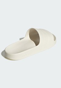 White slide sandal featuring a textured, rubber-like material, an open toe design, and three diagonal stripes on the upper. Subtle branding embossed.