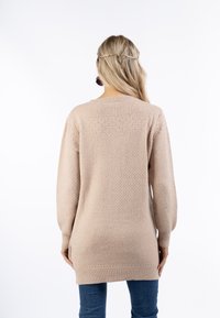 Beige kötött pulóver texturált mintával, hosszú ujjal és bordás mandzsettával. A háta kicsit hosszabb szabású, az alján.