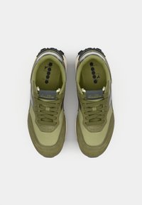 Olive green sneakers with mesh and suede upper, round toe, prominent laces, rubber accents, and textured soles. Diadora logo on tongue.