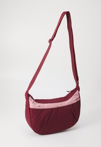 Bordeaux kleurige schoudertas met een lichtroze streep, gebogen vorm, verstelbare band en ritsluiting. Gladde textuur en casual ontwerp.