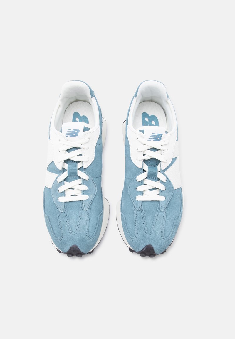 Paire de baskets New Balance bleues et blanches avec des lacets blancs, vue de dessus sur un fond clair uni.