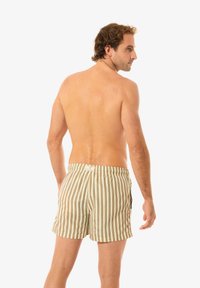 Randiga badshorts i beige och brunt med elastisk midja, sidofickor och medellång passform, med vertikala linjer.