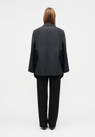 Sort skræddersyet jakkesæt med nålestribet design, med en lang, afslappet pasform jakke og bukser med brede ben. Glat stof og subtil glans.