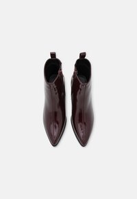 Bordowe lakierowane botki za kostkę z ostrym noskiem, gładką fakturą, bocznymi zamkami i pętelkami do ściągania, wyróżniające się eleganckim designem i dopasowanym kształtem.