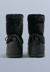 Sorte ankelstøvler foret med sort imiteret pels, med vandafvisende yderside, snørelukning og tekstureret gummisål for godt fodfæste. Kan foldes ned i toppen for stil.