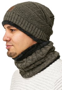 Grijze gebreide beanie met een textuurpatroon en een omgeslagen boord, vergezeld van een bijpassende geribbelde nekwarmer in donkergrijs.