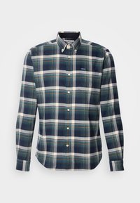 Chemise à manches longues à boutons avec un motif à carreaux vert, bleu marine, blanc et beige, et un col boutonné.