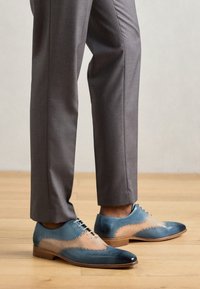 Scarpe eleganti in pelle bicolore con una combinazione di blu e tan, finitura liscia, punta appuntita e dettagli decorativi in brogue.