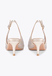 Scarpe con tacco alto beige, con una finitura metallica lucida, caratterizzate da una parte superiore gioiello, cinturino alla caviglia regolabile e un sottile tacco a spillo.