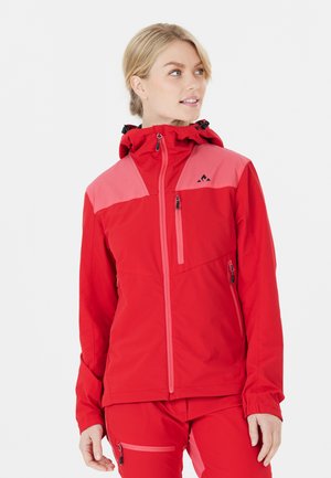 Veste extérieure rouge avec un design d'épaule rose, fermeture éclair à l'avant, capuche réglable et poches zippées pour le rangement.