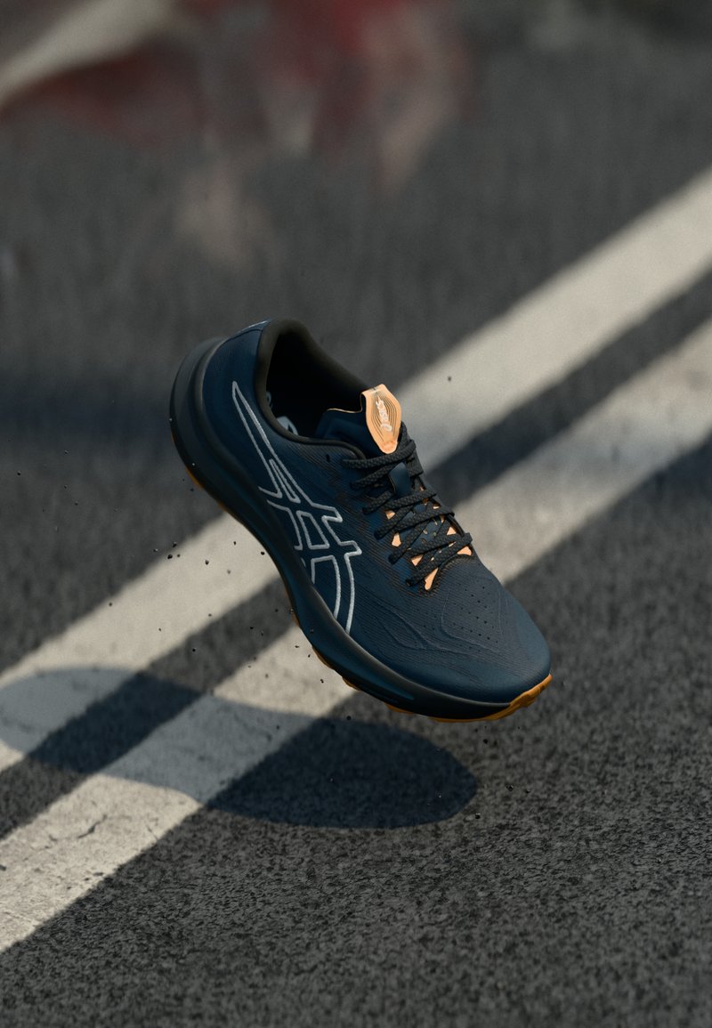 Chaussure de sport de couleur bleu marine foncé avec une surface texturée, des accents blancs et un logo orange au talon. Design léger avec des lacets.
