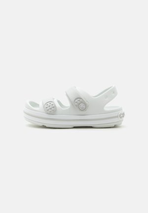 Sandale Crocs blanche à bout ouvert avec brides ajustables et trous de ventilation ronds sur une semelle plate, sur fond uni.