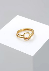 Anello in oro con design circolare, accentato da una pietra e due bande intrecciate, finitura lucida e cinque piccoli cristalli trasparenti.