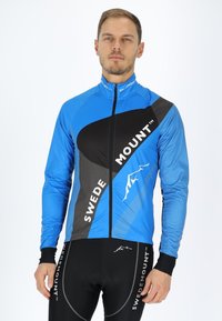 Blauwe fietsjack met zwarte accenten, volledige rits en contrasterende grijze patronen. Draagt een zwarte fietsbroek met logo-details.