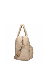 Beige kviltad väska med dubbla axelremmar, en framdragkedja och sidofickor. Tillverkad av mjukt material med en platt botten och justerbar rem.