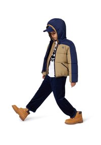 Giacca imbottita con parte superiore blu navy e parte inferiore beige, con cappuccio. Abbinata a pantaloni in corduroy blu navy e stivali beige con lacci. T-shirt bianca con grafica sotto.