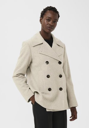 Light beige double-breasted wool coat with large black buttons, wide lapels, and side pockets. Relaxed fit and textured fabric.